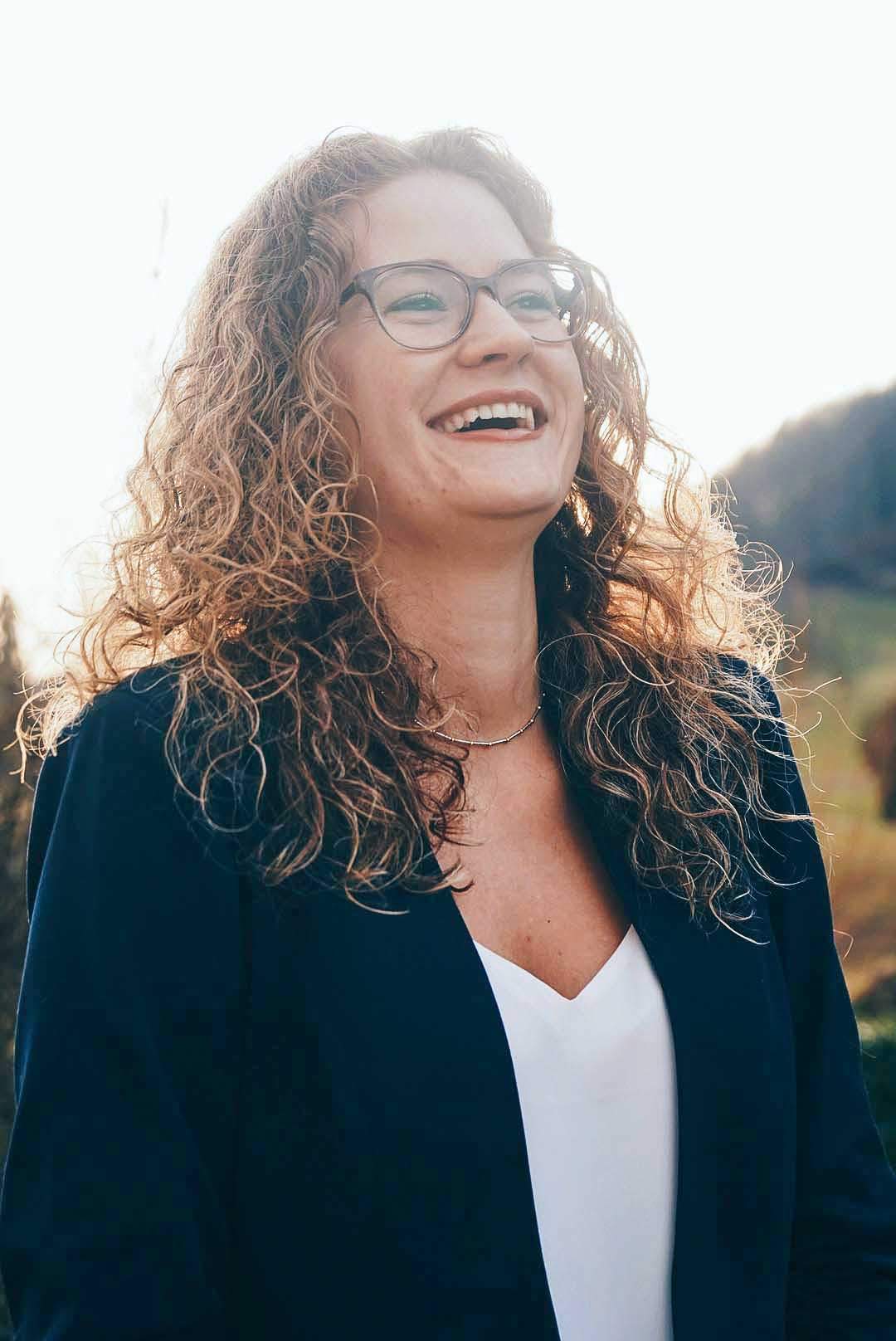 Junge Frau bei Sonnenuntergang, lachend und mit blonden locken.