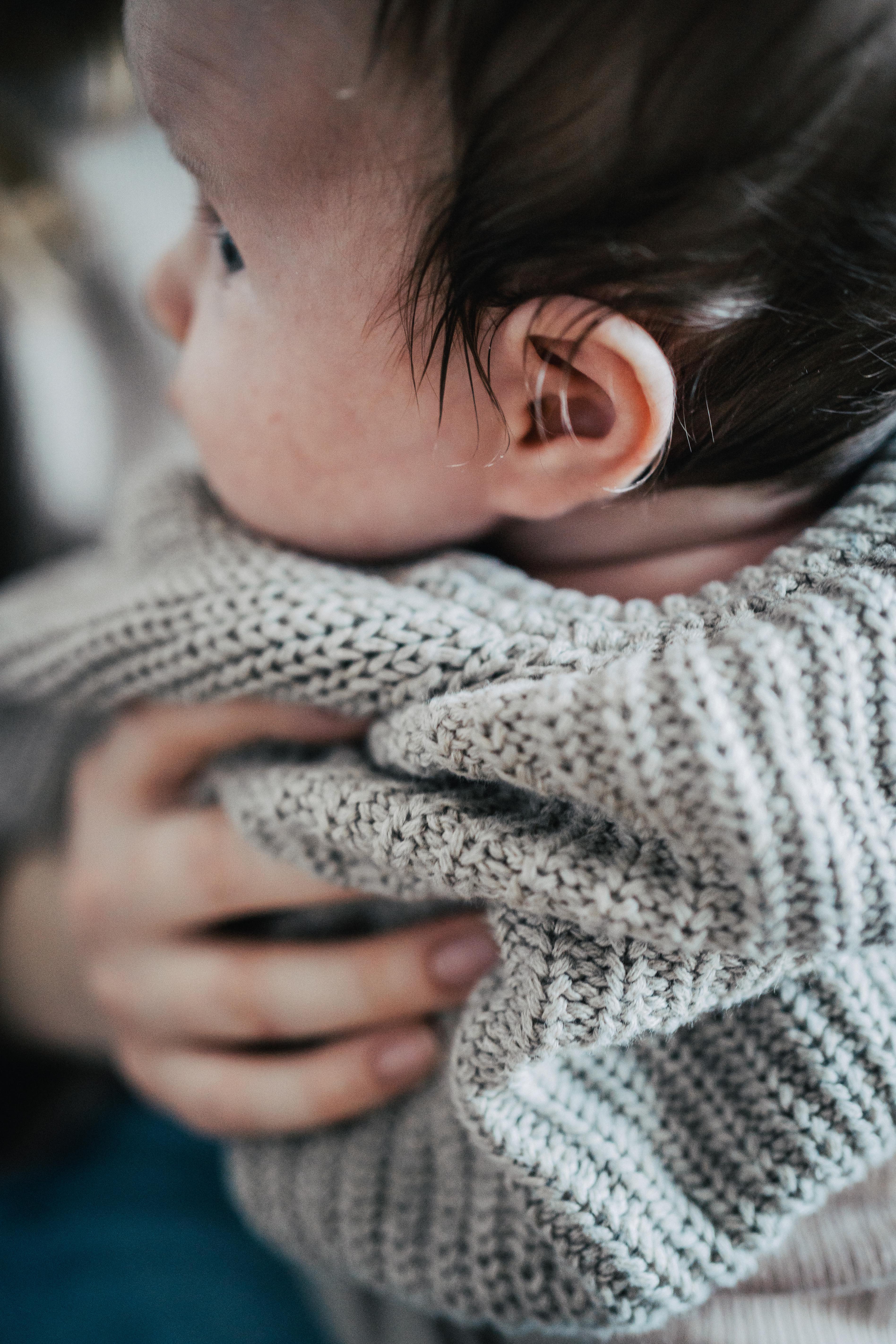 Auf dem Bild sieht man ein kleines Baby mädchen von der Seite mit den ihren Ohren