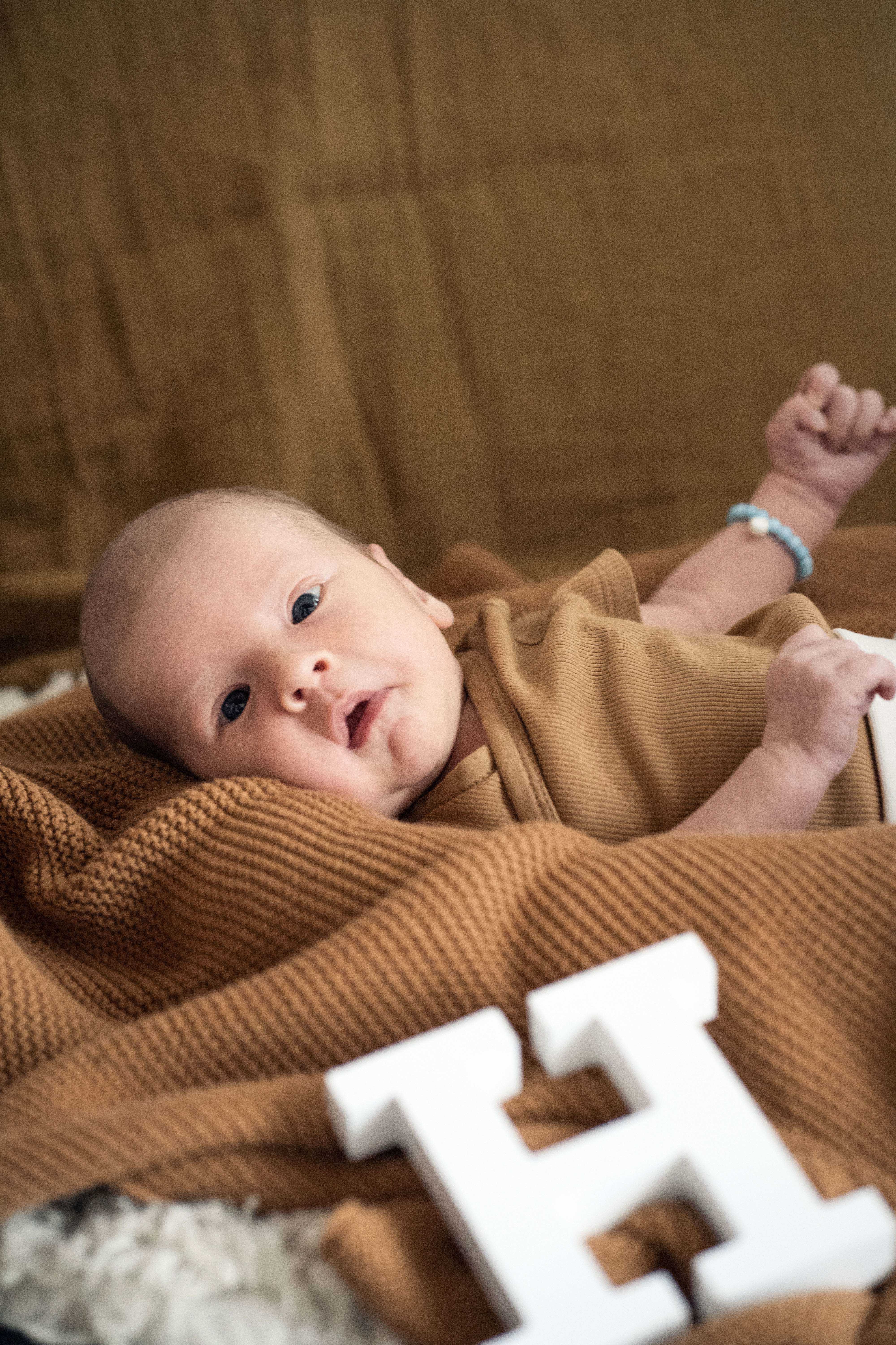 Baby liegt auf Kuscheldecke mit Buchstaben