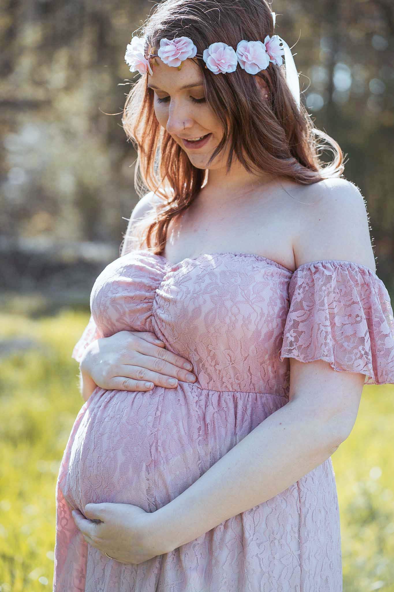 Schwanger junge Frau mit einem Kleid und einem Blumenkranz.