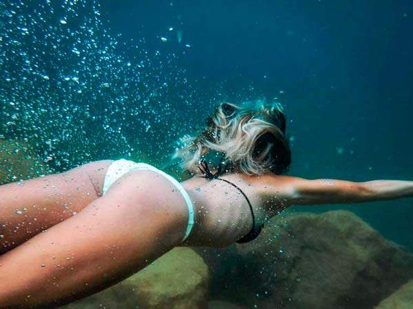 junge frau schwimmt unterwasser mit einem weiss schwarzen bikini