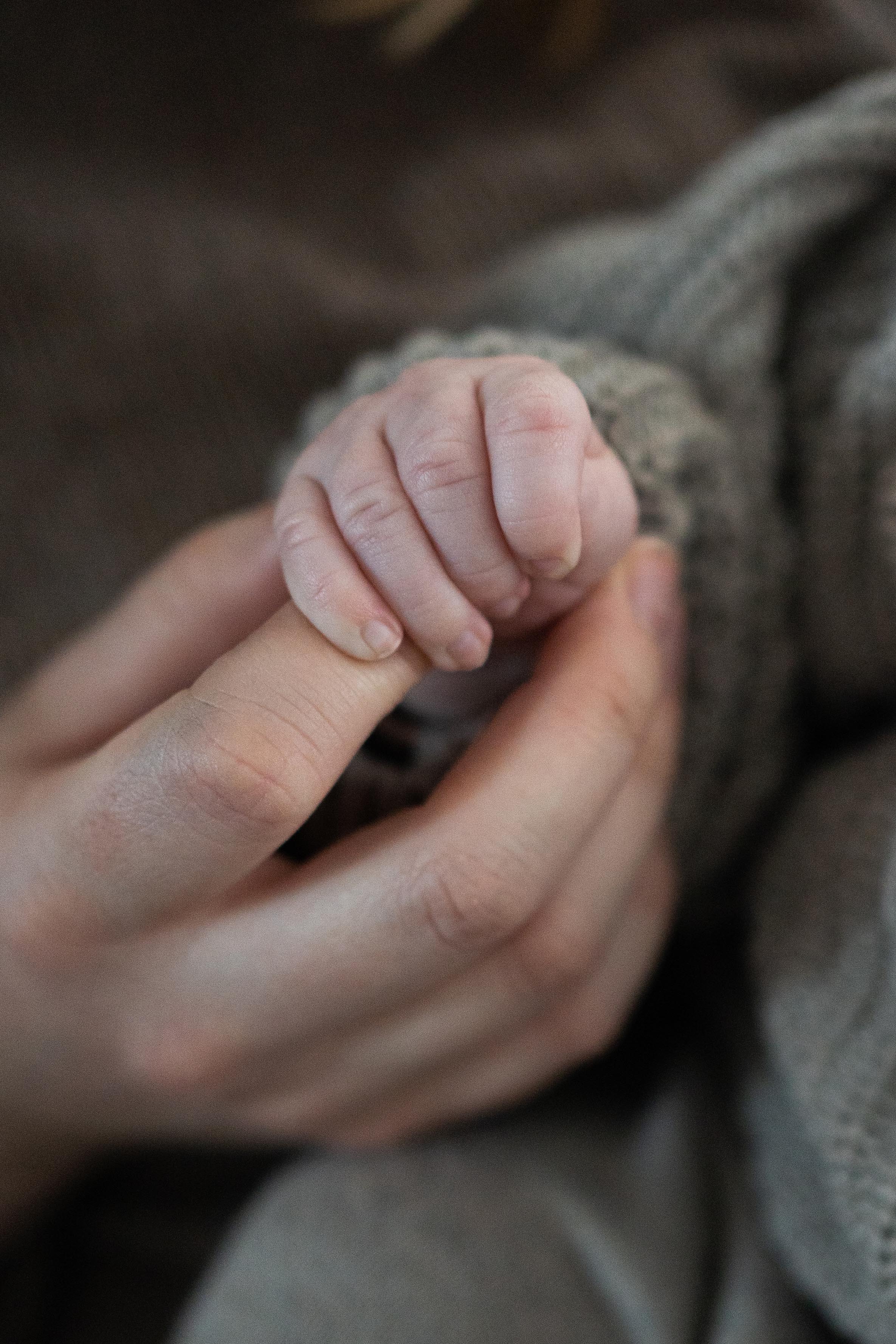 Babyshooting, Mammi hält die Hand ihres kleinen Babys