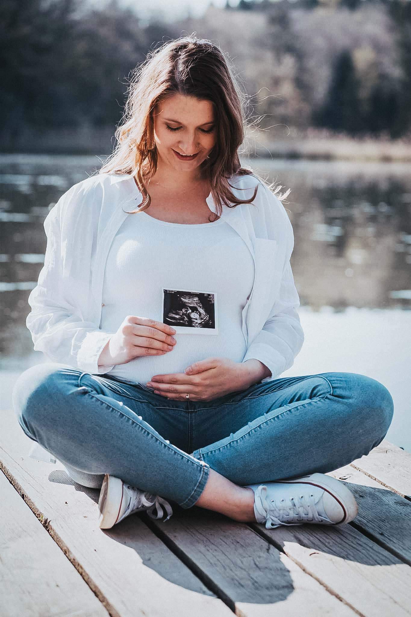 Schwangere Frau auf dem Steg mit einem Ultraschalfoto.