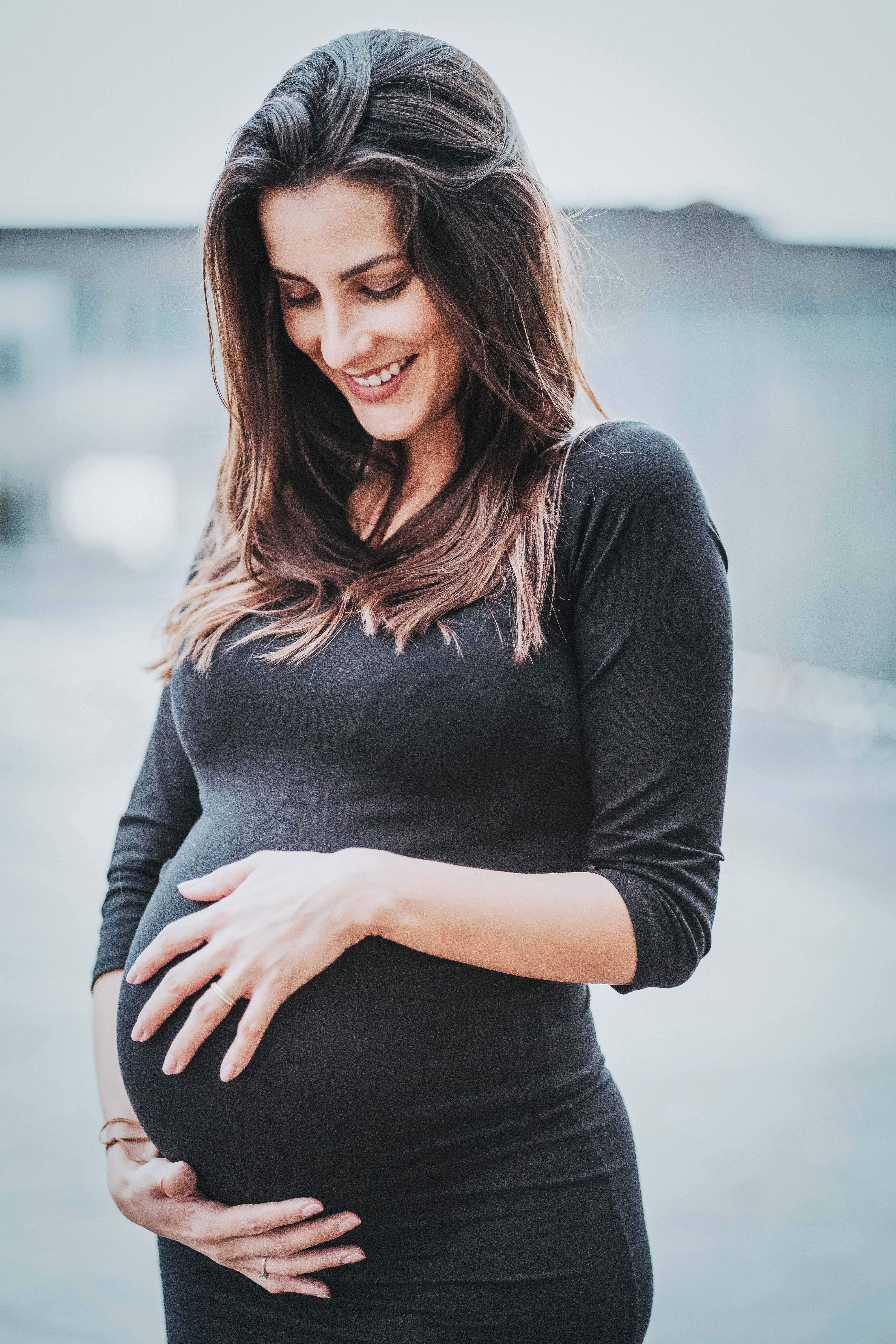 Junge Frau die sich den Schwangeren Bauch hält.