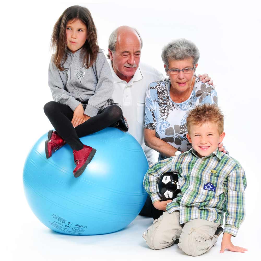 maedchen auf einem blauen sitzball. opa und oma und der kleine bruder nebenan